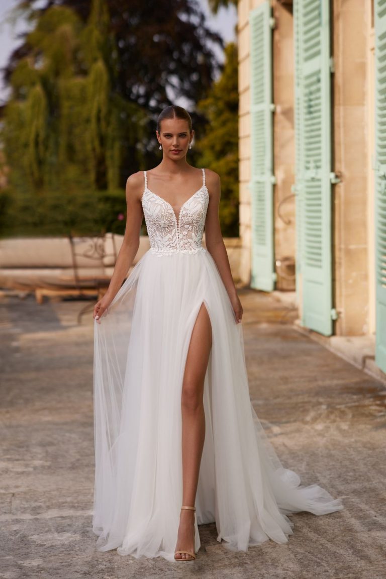 Vorderansicht eines A-Linien-Brautkleides mit floraler Spitze, tiefem V-Ausschnitt und fließendem Tüllrock mit hohem Schlitz.
