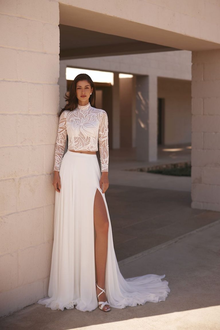 Brautkleid mit floraler Spitze, hochgeschlossenem Top und fließendem Rock mit Beinschlitz, Frontansicht.