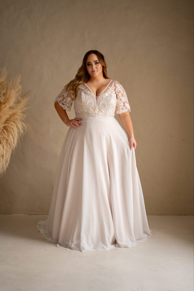 Plus-Size Brautkleid mit floraler Spitze, V-Ausschnitt und fließendem Chiffonrock in der Vorderansicht.