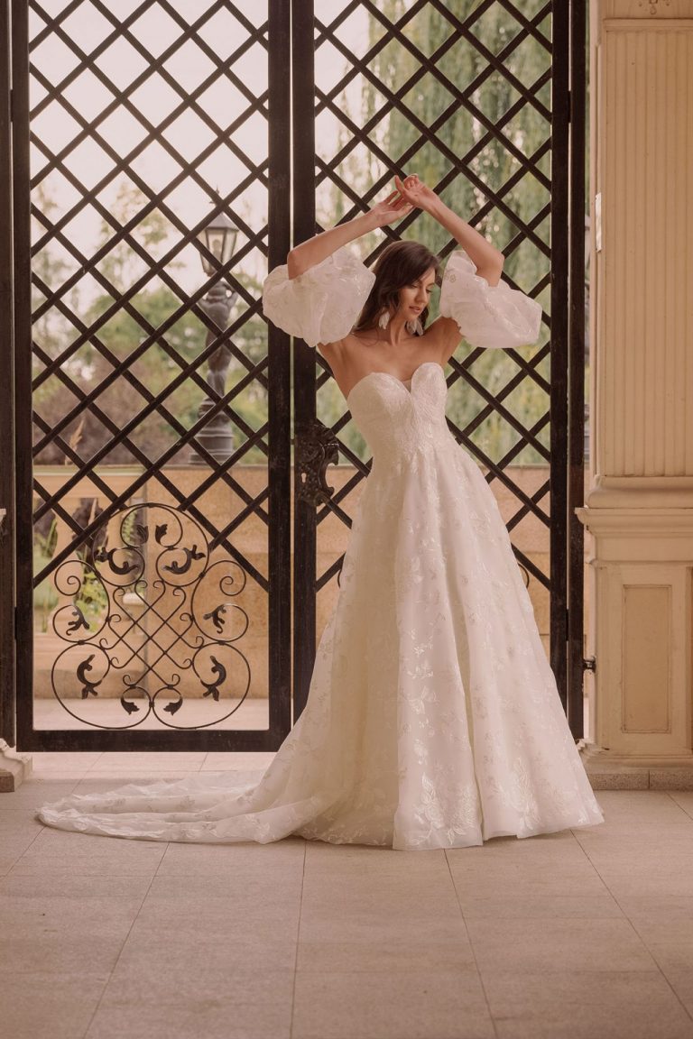 Brautkleid mit A-Linie, Herz-Ausschnitt und abnehmbaren Puffärmeln vor romantischem Gittertor
