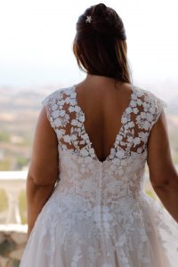 Rücken-Detail eines Prinzessinnen-Brautkleids: transparenter V-Rücken mit floraler Spitze und Cap-Sleeves in Ivory über Nude.
